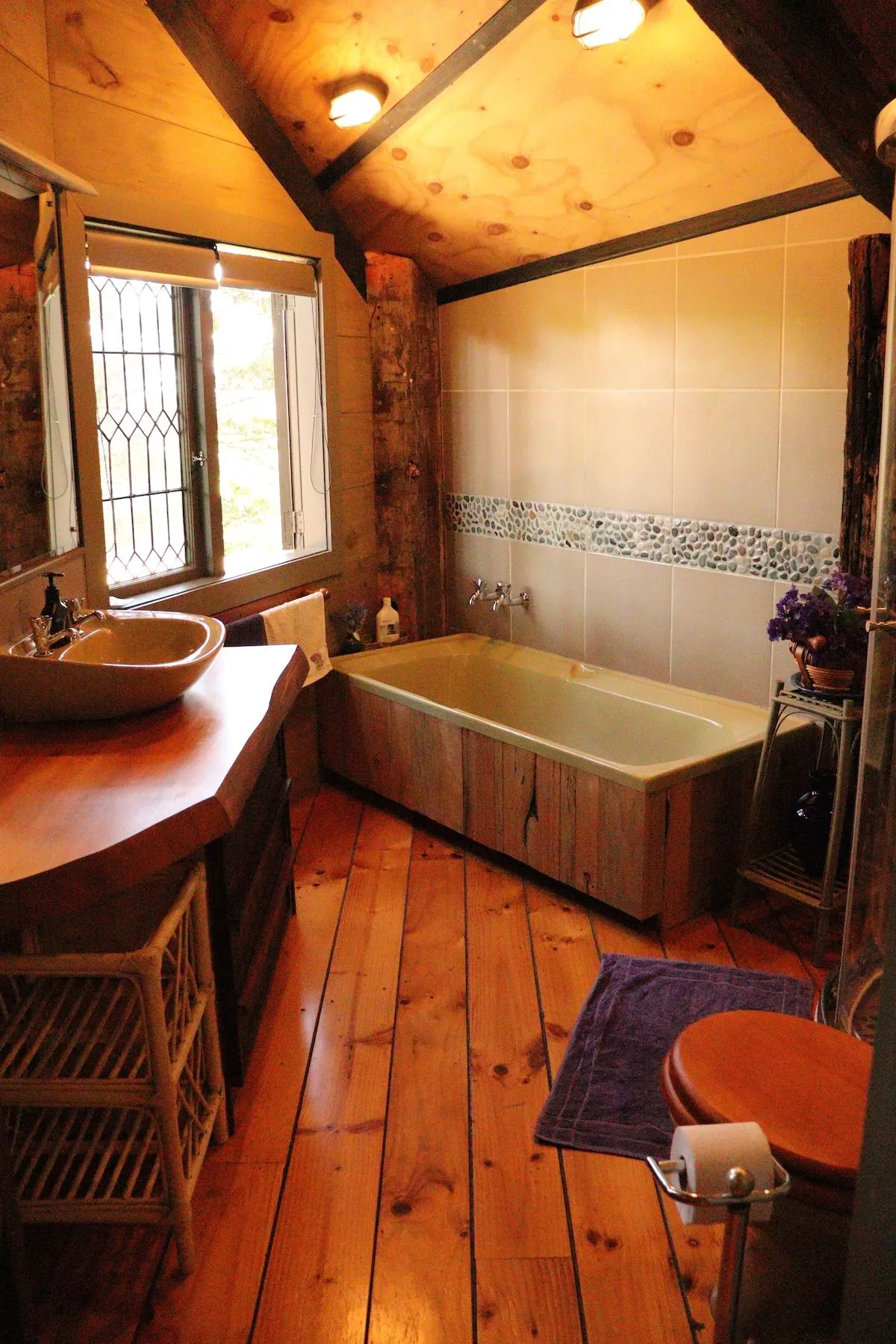 The bathroom, with a timber-panelled bath and a vessel basin.