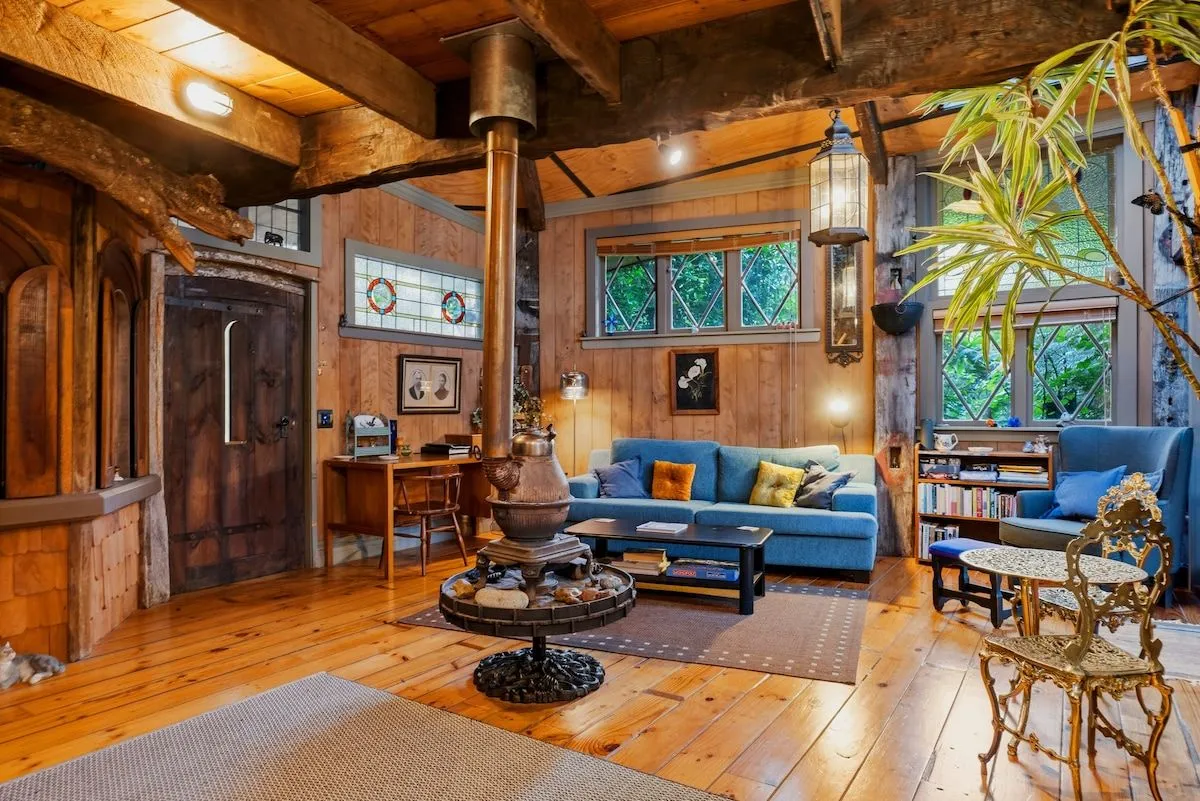 The lounge, with blue sofas, patterned rugs, a pot-belly stove and stained-glass windows set in timber walls.