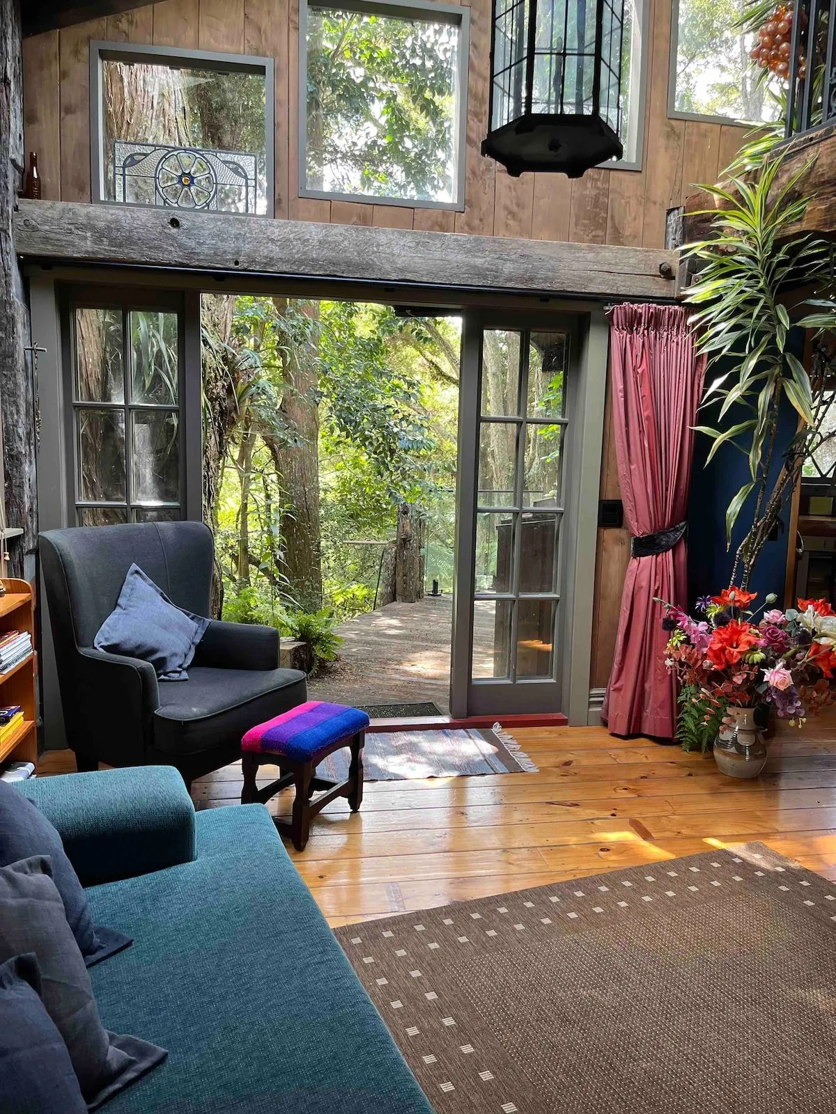 Armchairs beside open french doors, looking out into green bush.