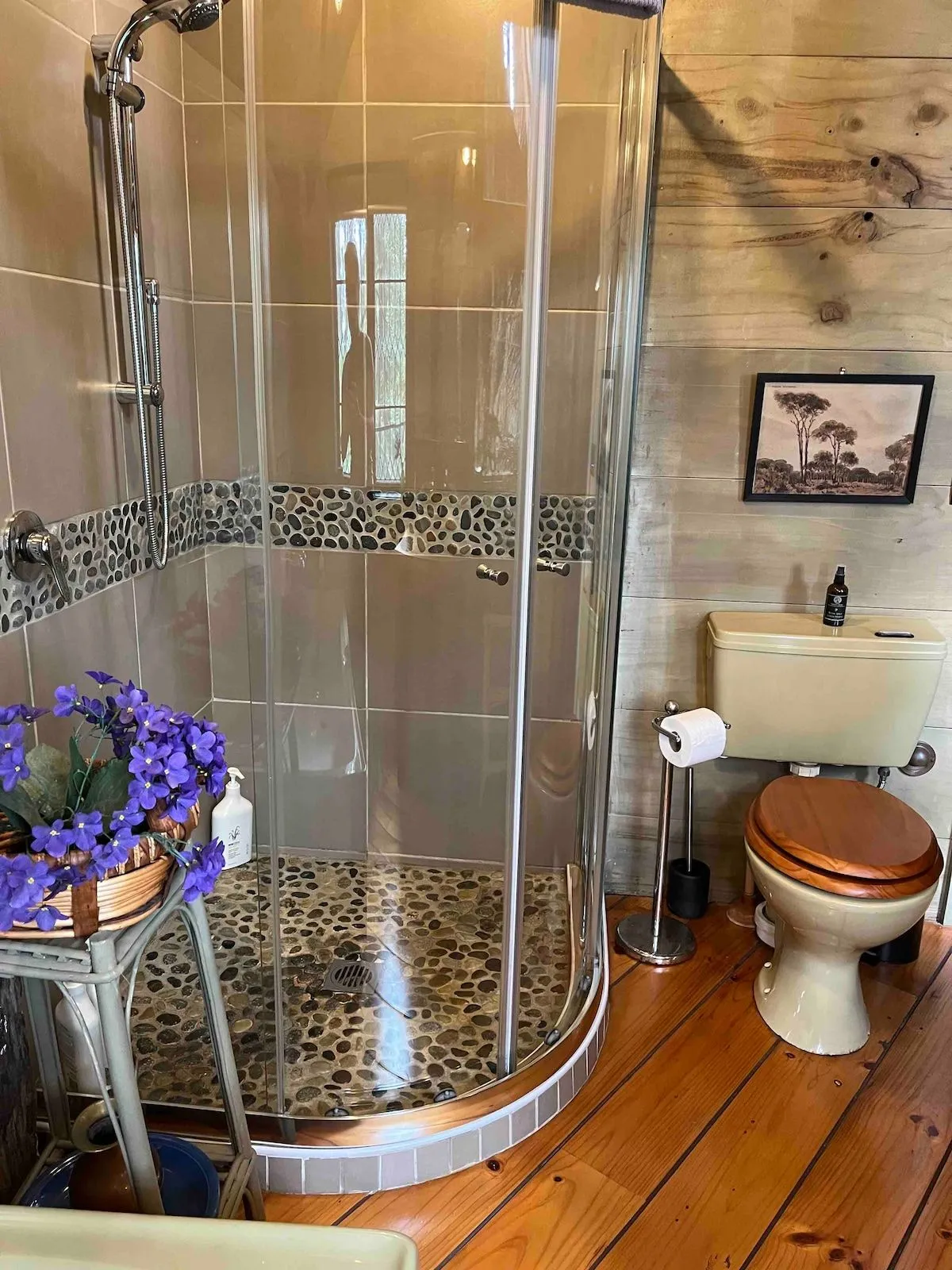 The curved glass shower, set on a timber floor with mosaic tiling.