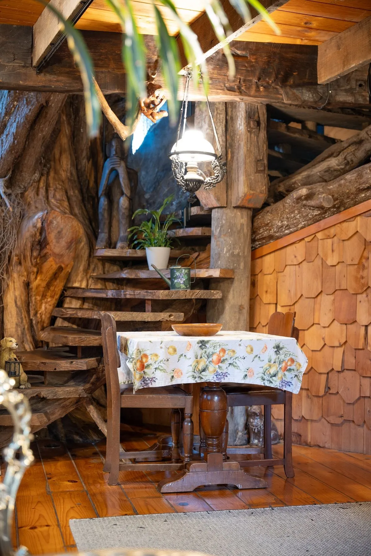 Timber stairs rising past a laid table, with branches worked into the structure.