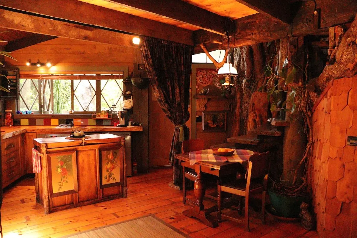 The timber kitchen with a tiled splashback and dining table alongside.